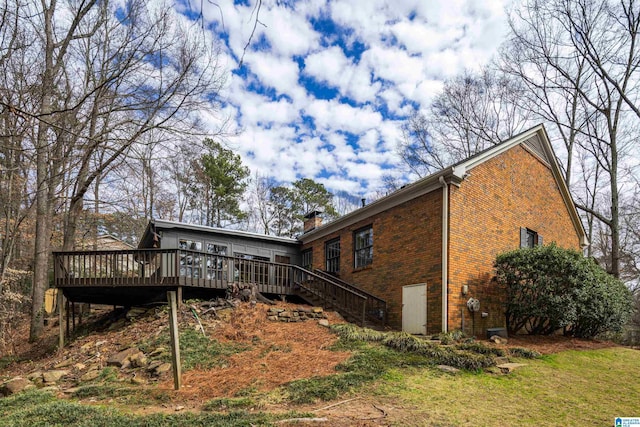 rear view of property with a deck, brick siding, and stairway