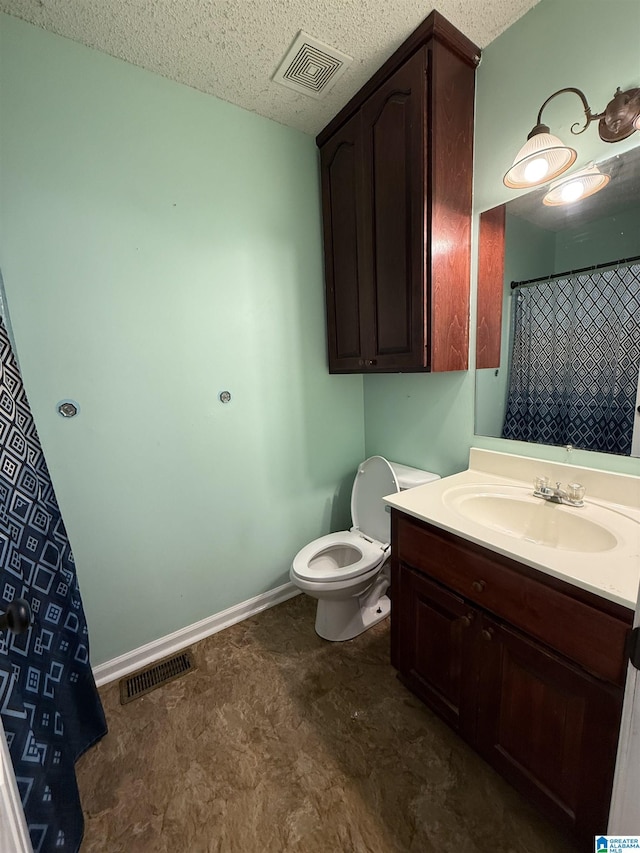 bathroom with toilet, vanity, visible vents, and baseboards