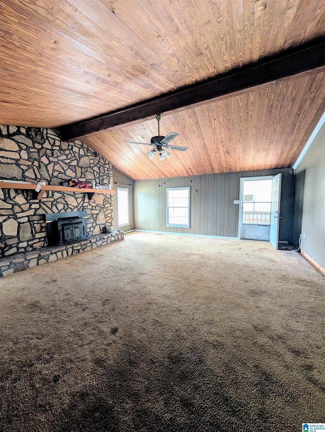 unfurnished living room featuring vaulted ceiling with beams, wood ceiling, carpet flooring, and a wood stove