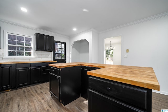 kitchen with tasteful backsplash, crown molding, wooden counters, a center island, and light hardwood / wood-style flooring