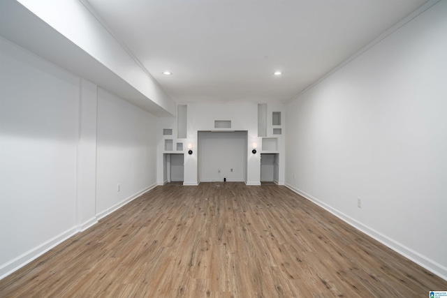 unfurnished living room featuring built in features and light wood-type flooring