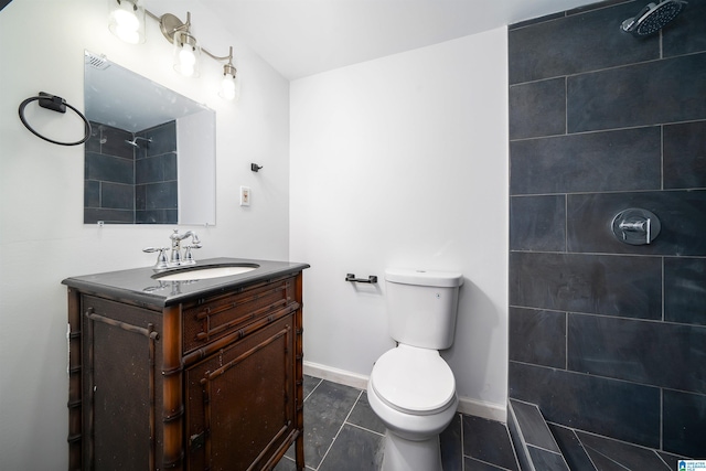 bathroom featuring tiled shower, vanity, toilet, and tile patterned flooring