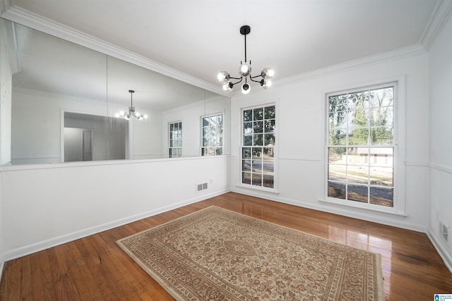 unfurnished dining area featuring ornamental molding, wood-type flooring, and a notable chandelier