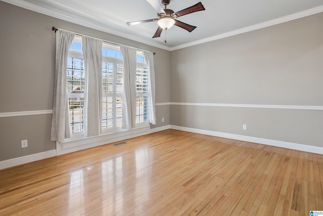 spare room featuring ceiling fan, wood finished floors, visible vents, baseboards, and crown molding