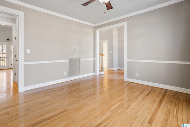 spare room with light wood-style flooring, a ceiling fan, visible vents, baseboards, and ornamental molding