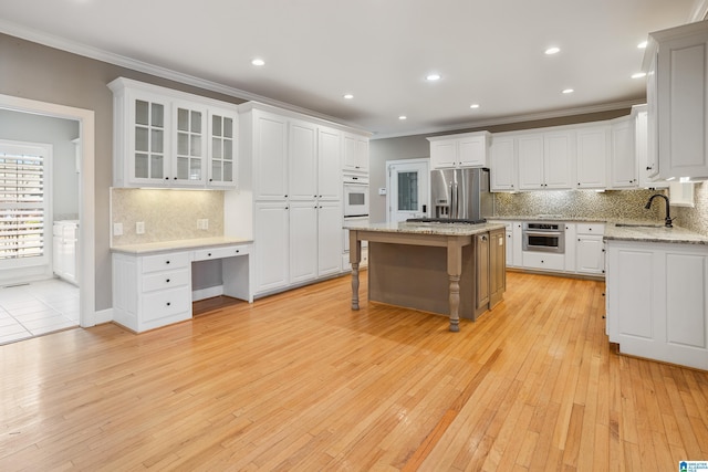 kitchen with built in desk, stainless steel refrigerator with ice dispenser, a breakfast bar area, a sink, and a kitchen island