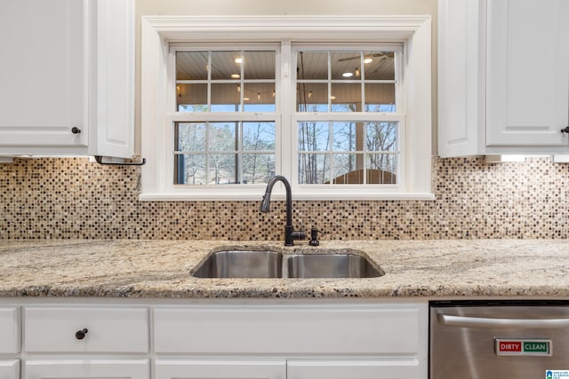 kitchen with a sink, tasteful backsplash, white cabinets, and stainless steel dishwasher