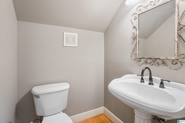 bathroom with toilet, baseboards, a sink, and wood finished floors