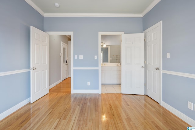 unfurnished bedroom with light wood-style floors, ornamental molding, baseboards, and ensuite bathroom