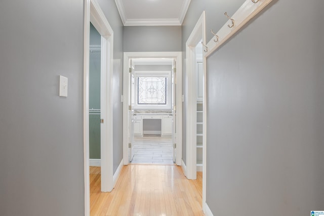 hall with light wood finished floors, baseboards, and ornamental molding