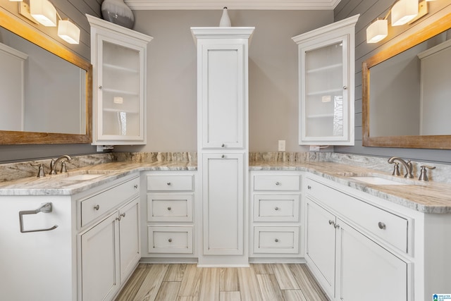 bathroom with ornamental molding, two vanities, and a sink