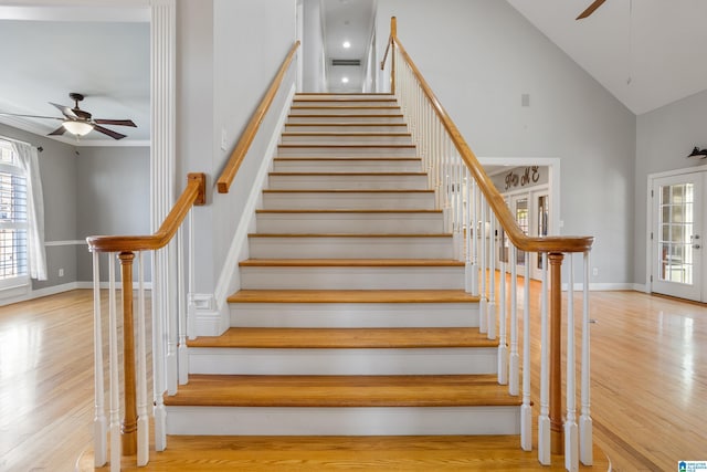 stairs featuring a ceiling fan, high vaulted ceiling, baseboards, and wood finished floors