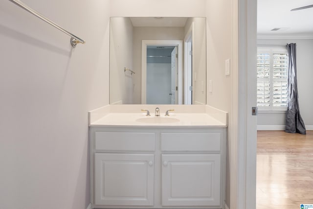 bathroom featuring crown molding, baseboards, wood finished floors, and vanity