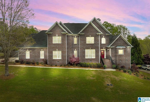 view of front of property with crawl space, brick siding, and a lawn