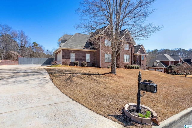 view of front facade featuring an attached garage, brick siding, a shingled roof, fence, and driveway