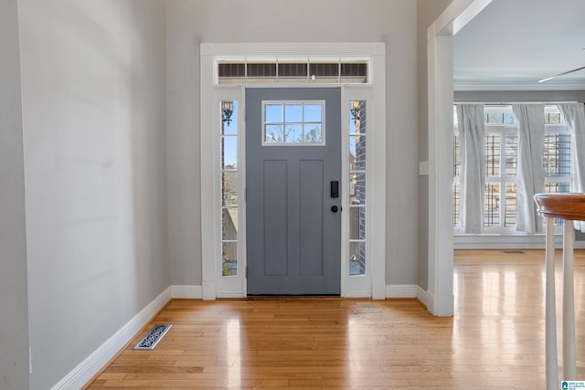 foyer featuring light wood finished floors, baseboards, and visible vents