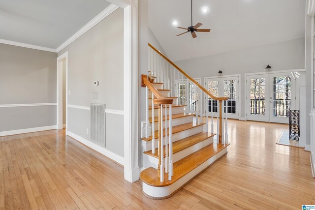 stairs featuring visible vents, ornamental molding, hardwood / wood-style floors, french doors, and high vaulted ceiling