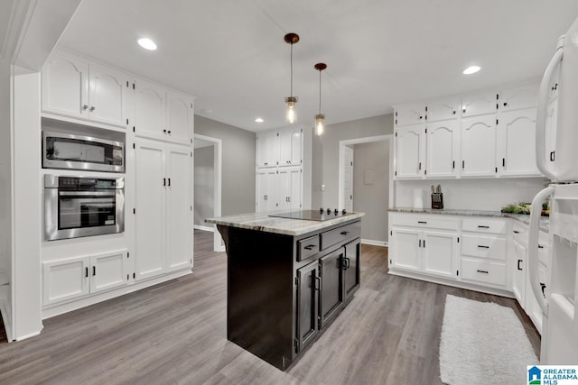 kitchen with a kitchen island, light stone countertops, appliances with stainless steel finishes, and pendant lighting