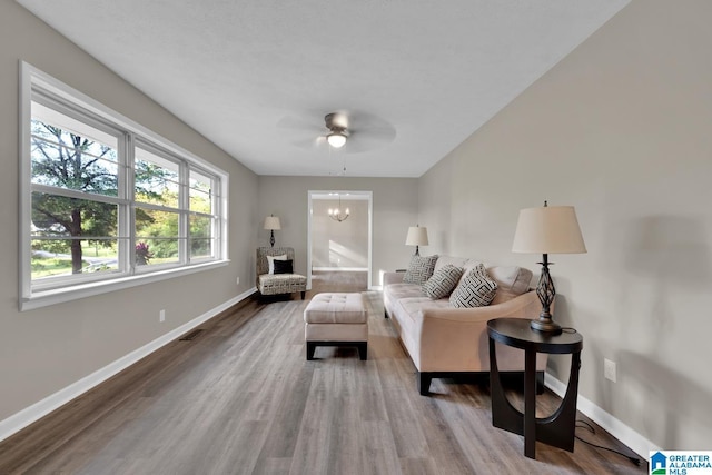 living room with hardwood / wood-style flooring and ceiling fan with notable chandelier