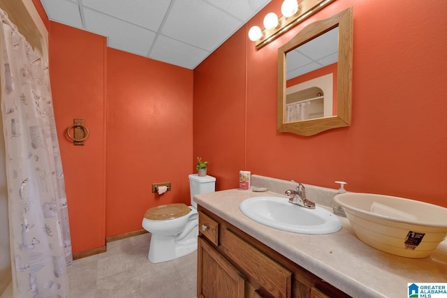 bathroom featuring vanity, toilet, and a drop ceiling