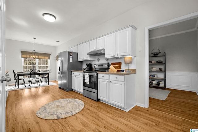 kitchen featuring light wood-type flooring, white cabinetry, stainless steel appliances, and pendant lighting