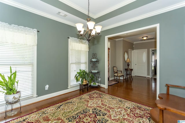 interior space with an inviting chandelier, dark wood-type flooring, ornamental molding, and a raised ceiling