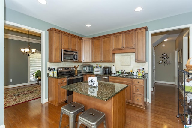 kitchen with sink, a breakfast bar, dark stone countertops, stainless steel appliances, and a kitchen island