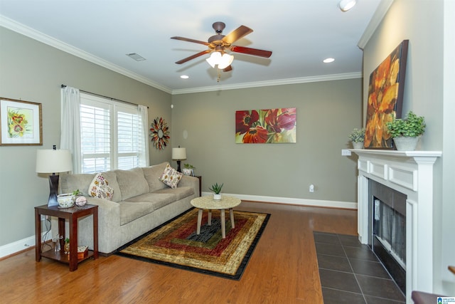 living room featuring a tile fireplace, ornamental molding, ceiling fan, and dark hardwood / wood-style flooring