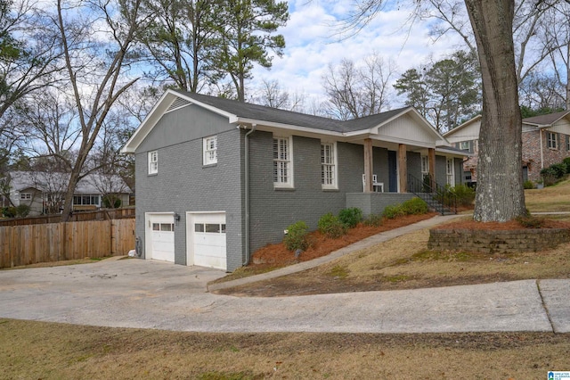 view of front of house featuring a garage, covered porch, brick siding, fence, and driveway