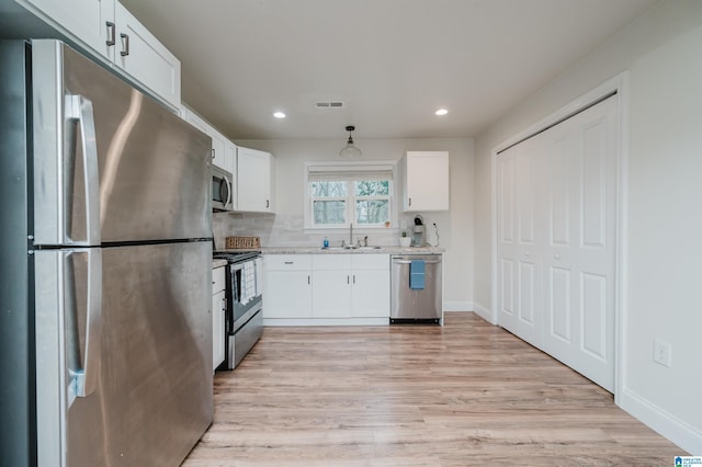 kitchen featuring sink, stainless steel appliances, white cabinets, and light wood-type flooring