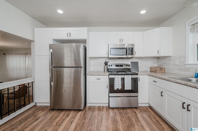 kitchen featuring white cabinetry, appliances with stainless steel finishes, hardwood / wood-style floors, and tasteful backsplash