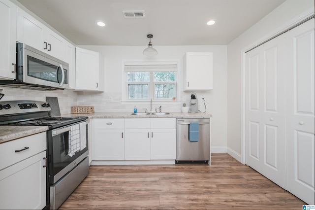 kitchen with white cabinetry, appliances with stainless steel finishes, decorative light fixtures, and sink