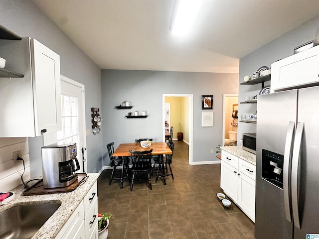 kitchen featuring appliances with stainless steel finishes, light stone countertops, white cabinets, and open shelves