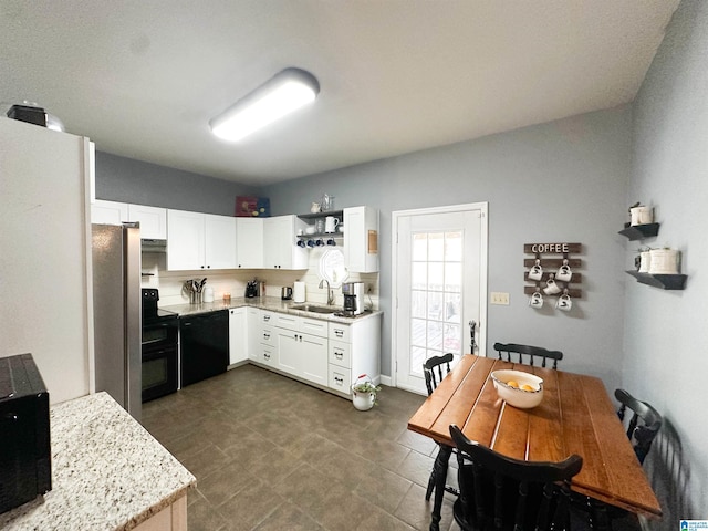 kitchen featuring light stone counters, under cabinet range hood, a sink, white cabinets, and black appliances