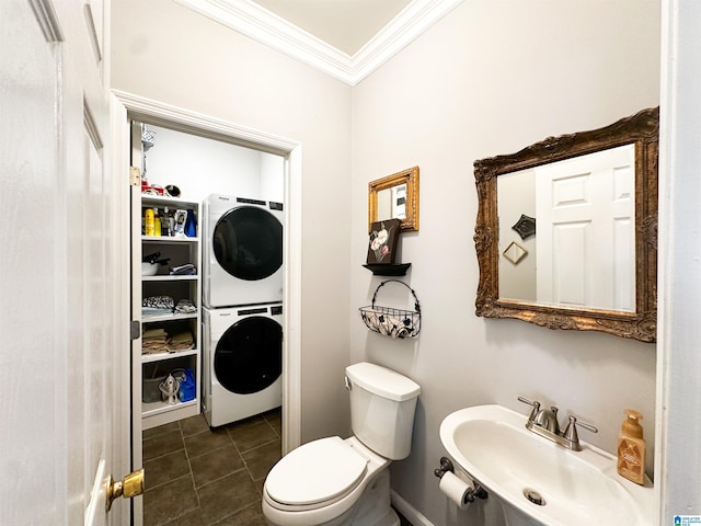 half bathroom with stacked washer / dryer, toilet, ornamental molding, tile patterned flooring, and a sink