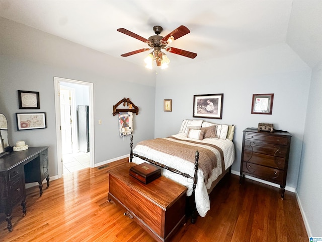 bedroom with ceiling fan, visible vents, baseboards, and wood finished floors