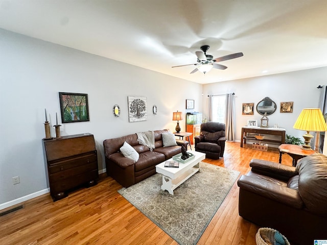 living area featuring a ceiling fan, light wood-type flooring, visible vents, and baseboards