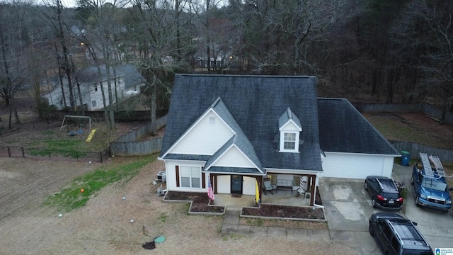 view of front of property featuring an attached garage, fence private yard, a shingled roof, and concrete driveway