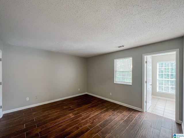 spare room featuring dark hardwood / wood-style flooring and a textured ceiling