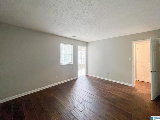 unfurnished room featuring dark hardwood / wood-style floors and a textured ceiling