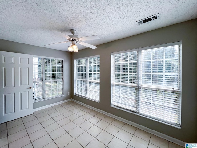 spare room with light tile patterned flooring, ceiling fan, and a textured ceiling