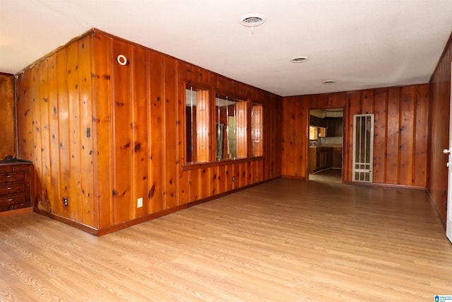 spare room featuring light hardwood / wood-style flooring and wooden walls