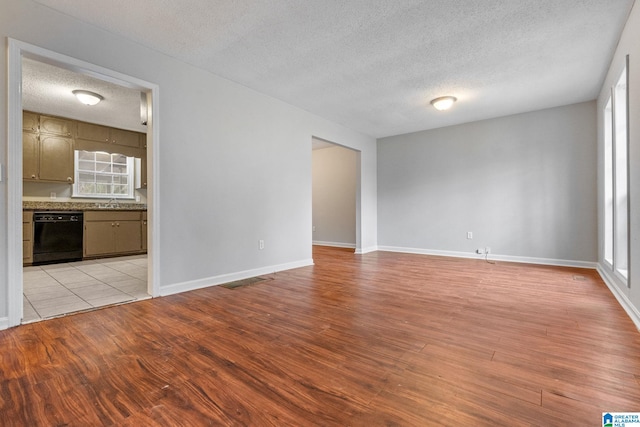 unfurnished living room featuring sink, a textured ceiling, and light wood-type flooring