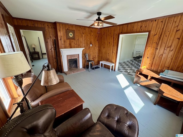 living room featuring ceiling fan, ornamental molding, a brick fireplace, and wood walls