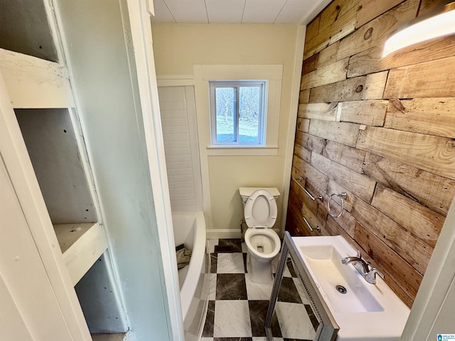 bathroom featuring vanity, a bath, wooden walls, and toilet