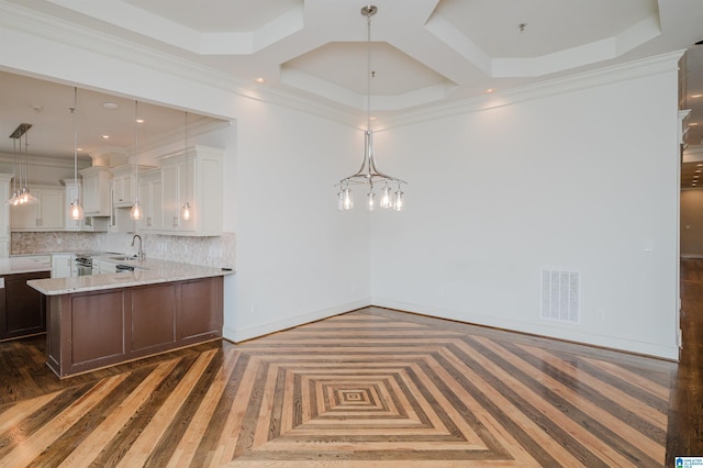 kitchen featuring white cabinetry, backsplash, hanging light fixtures, and light stone counters