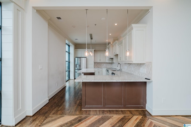 kitchen featuring tasteful backsplash, hanging light fixtures, light stone counters, white cabinets, and kitchen peninsula