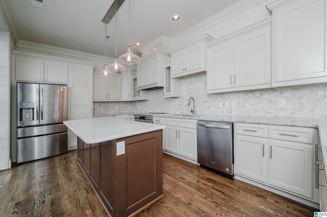 kitchen featuring stainless steel appliances, white cabinets, pendant lighting, a center island, and backsplash