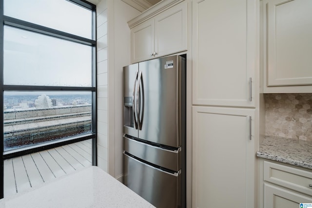 kitchen with decorative backsplash, white cabinetry, light stone counters, and stainless steel fridge with ice dispenser