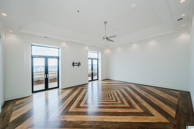 empty room with french doors, dark parquet flooring, ceiling fan, crown molding, and a tray ceiling